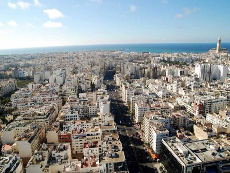Aerial view of Casablanca, Morocco, showcasing a bustling urban landscape with modern buildings and a glimpse of the coastline.
