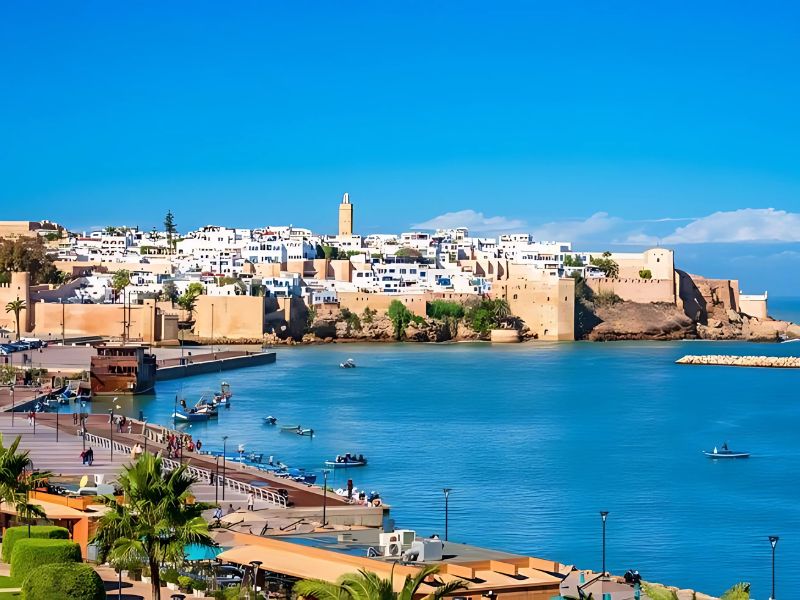 View of the Kasbah of the Udayas in Rabat, Morocco, featuring its historic walls, white buildings, and a clear blue sky.