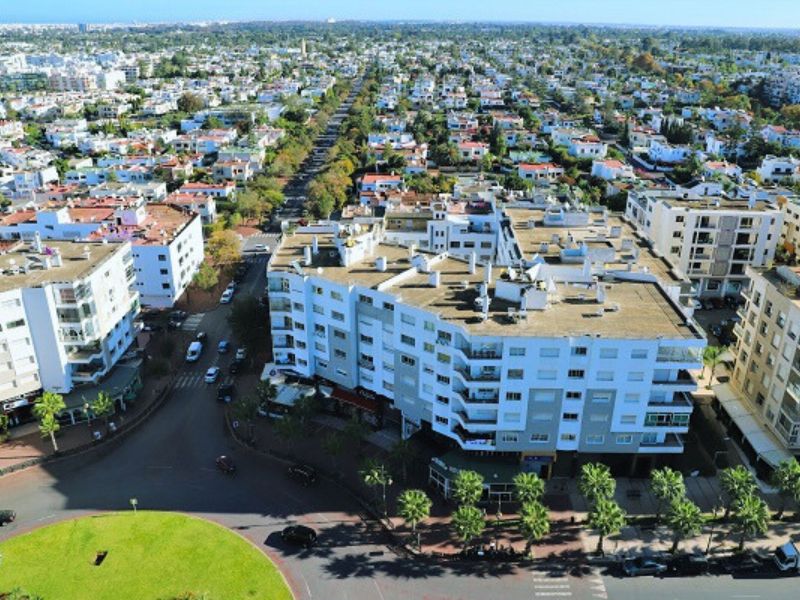 Aerial view of a residential area in Rabat, Morocco, showcasing a mix of modern and traditional architecture with palm trees lining the streets.