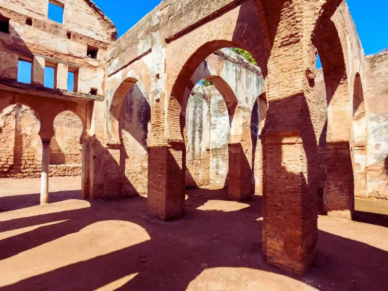 Interior view of the ancient ruins at Chellah, showcasing brick arches and columns under a clear blue sky.