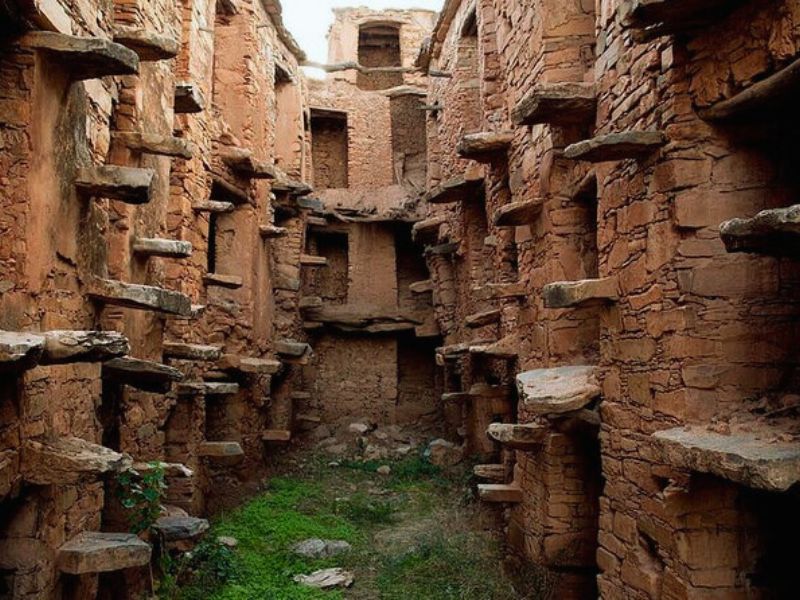 Interior view of an ancient granary in Morocco, featuring stone walls and stone shelves used for grain storage.