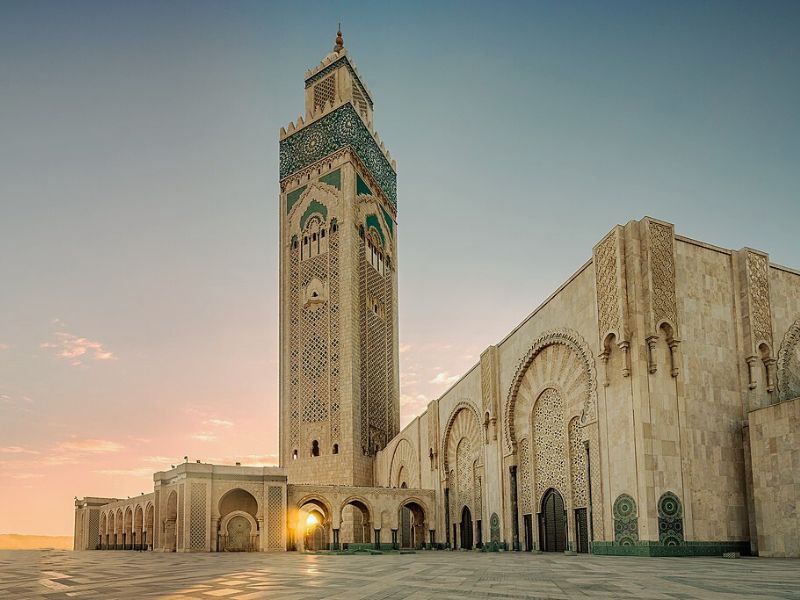 The Hassan II Mosque showcasing its towering minaret and intricate architectural details against a sunset backdrop in Casablanca, Morocco.