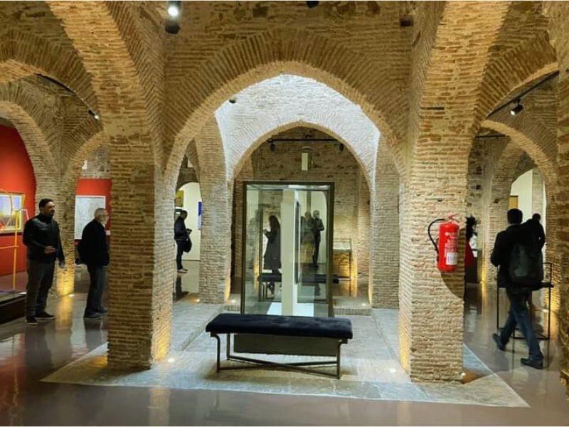Interior view of the Kasbah Museum in Tangier, showcasing exposed brick archways, modern displays, and visitors engaging with the exhibits.