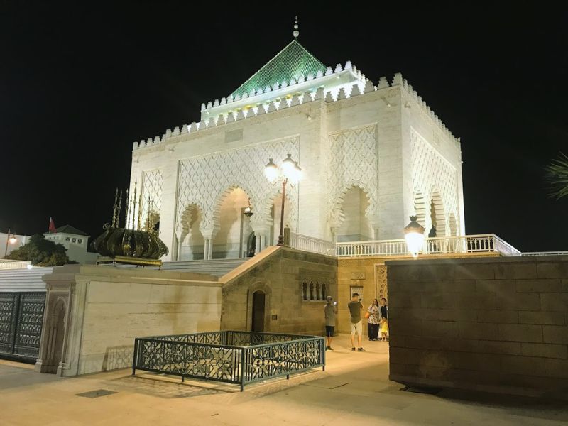 Night view of the Mohammed V Mausoleum in Rabat, Morocco, showcasing its stunning architecture with intricate details, illuminated by lights.