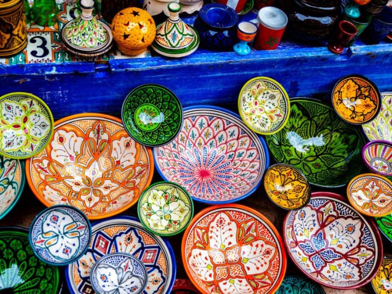 Colorful Moroccan pottery displayed in a variety of shapes, including bowls and tagines, featuring intricate patterns and vibrant glazes.