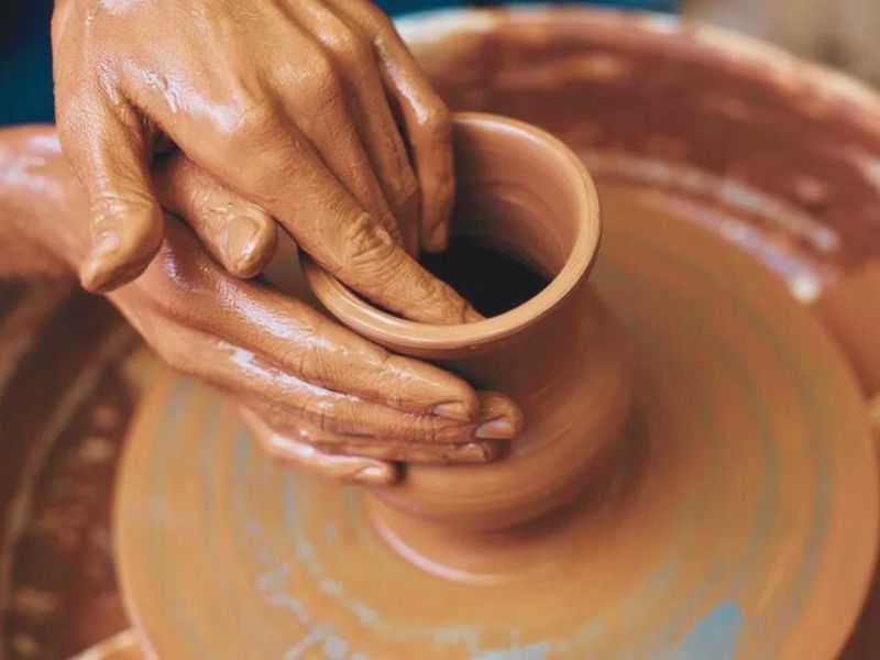 Hands skillfully shaping a clay pot on a pottery wheel, showcasing the traditional craft of Moroccan pottery.