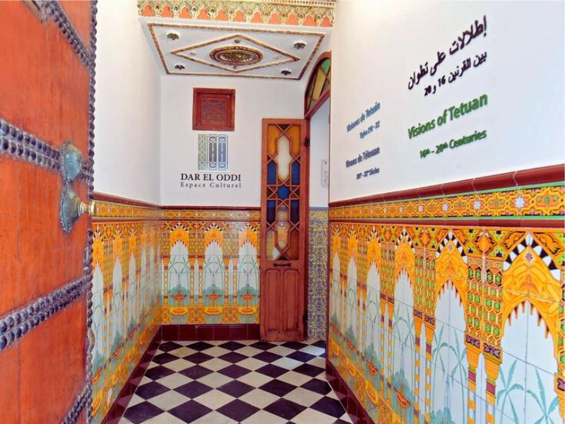 Entrance hallway of the Ethnographic Museum of Tetouan featuring ornate tilework and a traditional wooden door.