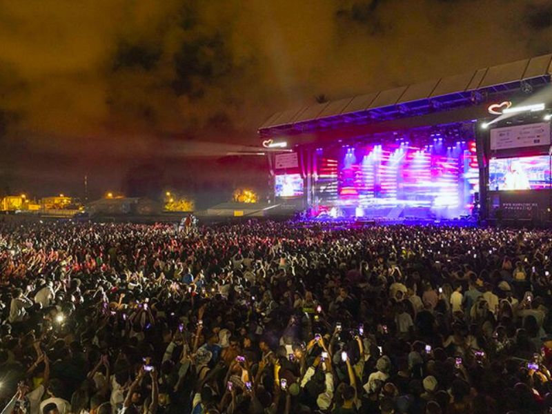 A vibrant crowd at the Mawazine Rhythms of the World Festival in Rabat, Morocco, with a large stage illuminated by colorful lights during a nighttime performance.