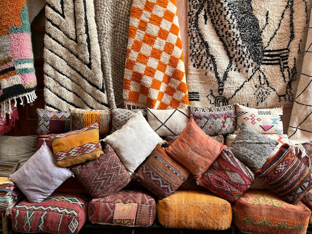 A collection of colorful Moroccan rugs and pillows displayed on a couch, showcasing various intricate patterns and textures.
