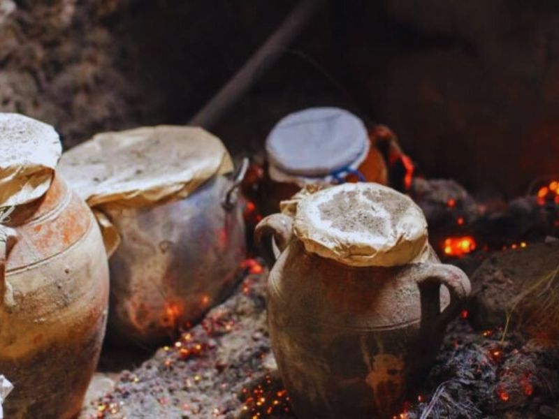 Traditional Moroccan Tanjia cooking pots nestled in hot ashes, demonstrating the unique communal cooking method of this iconic dish.