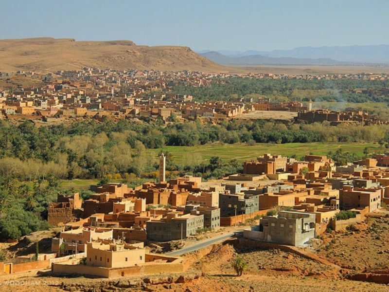 A panoramic view of the Dades Valley in Morocco, showcasing traditional mud-brick villages, lush green oases, and rugged mountain landscapes.