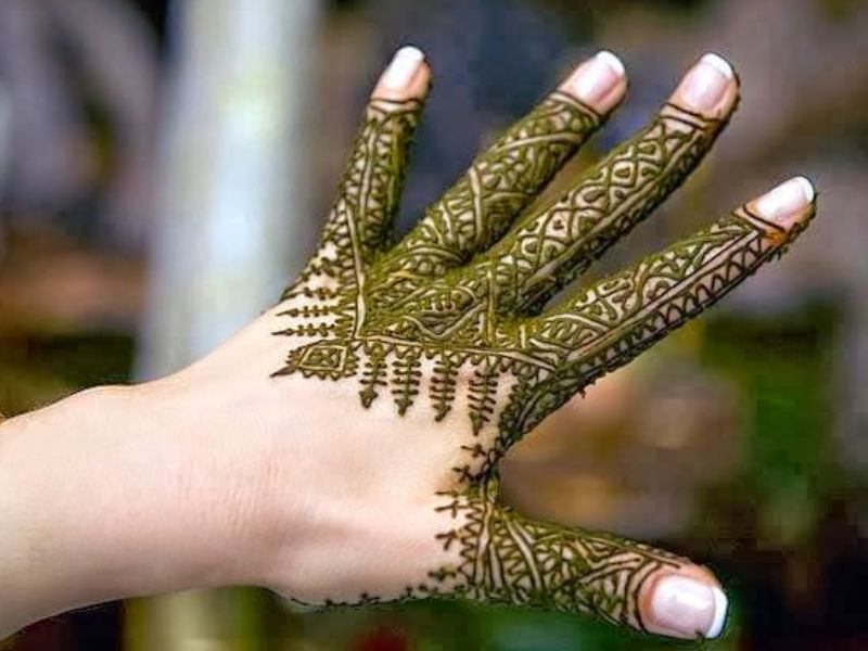 A hand adorned with intricate green Henna designs, showcasing traditional Moroccan patterns.