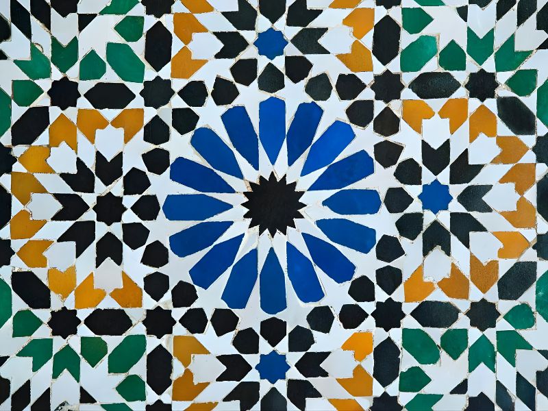 A colorful Zellige mosaic featuring intricate geometric patterns in blue, black, green, orange, and white, showcasing traditional Moroccan tilework.