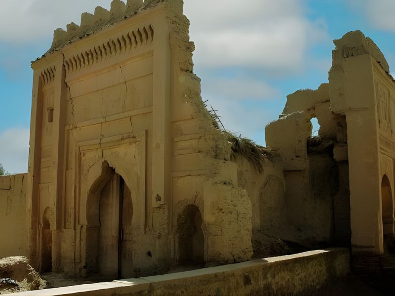 Ruins of ancient architecture in Sijilmasa, showcasing crumbling walls and arches under a blue sky.