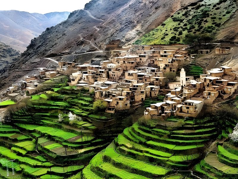 A picturesque village nestled amid terraced fields and rugged mountain landscapes, showcasing the natural beauty of the Moroccan Highlands.