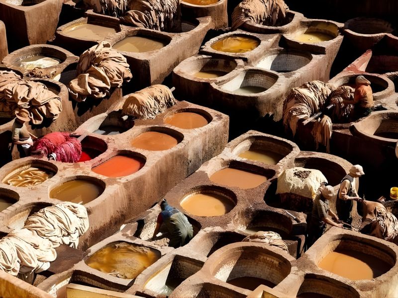 Aerial view of traditional leather tanning pits, with workers processing hides in vibrant, colorful dyes.