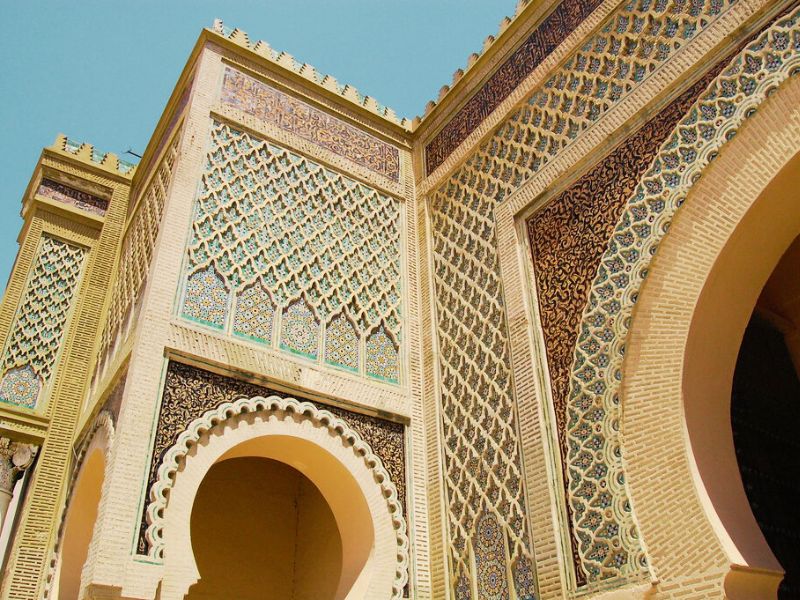 Close-up of ornate architectural details on a wall featuring intricate geometric patterns and colorful tile work, with arched openings.