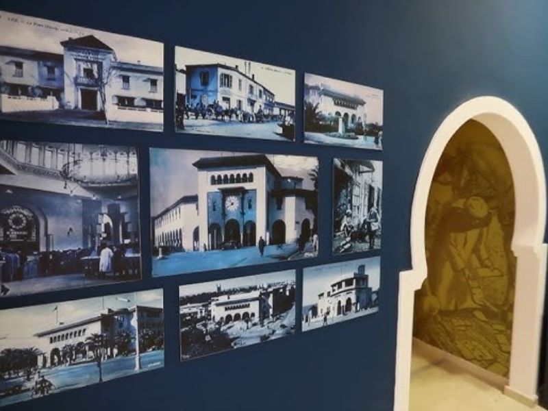 A wall featuring a collection of historical black-and-white photographs displayed in blue tones, showcasing architectural landmarks and scenes from the past, alongside a decorative arch leading to a different area.