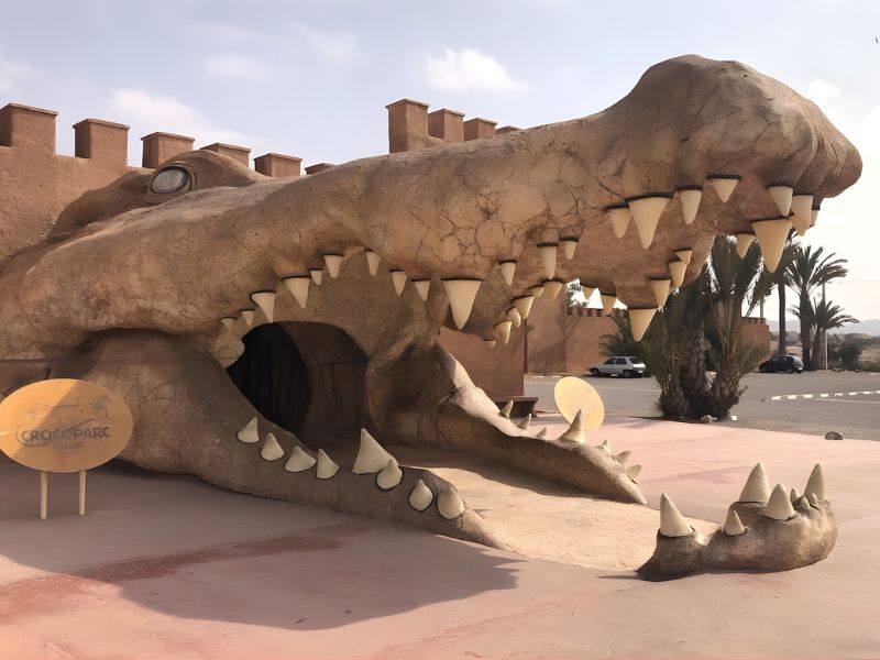 Entrance of Crocoparc, featuring a large crocodile sculpture with an open mouth and sharp teeth.