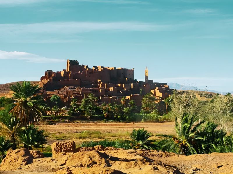 Ancient fortified village made of mud brick on a hill with palm trees and desert landscape