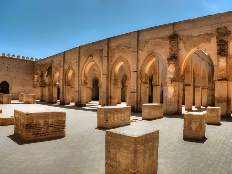 Courtyard with ancient stone columns and archways under clear blue sky